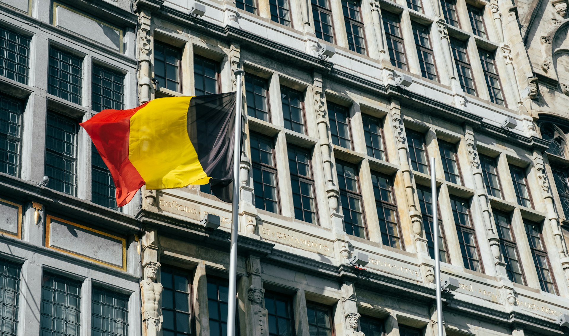 a Belgian flag flying in front of a building